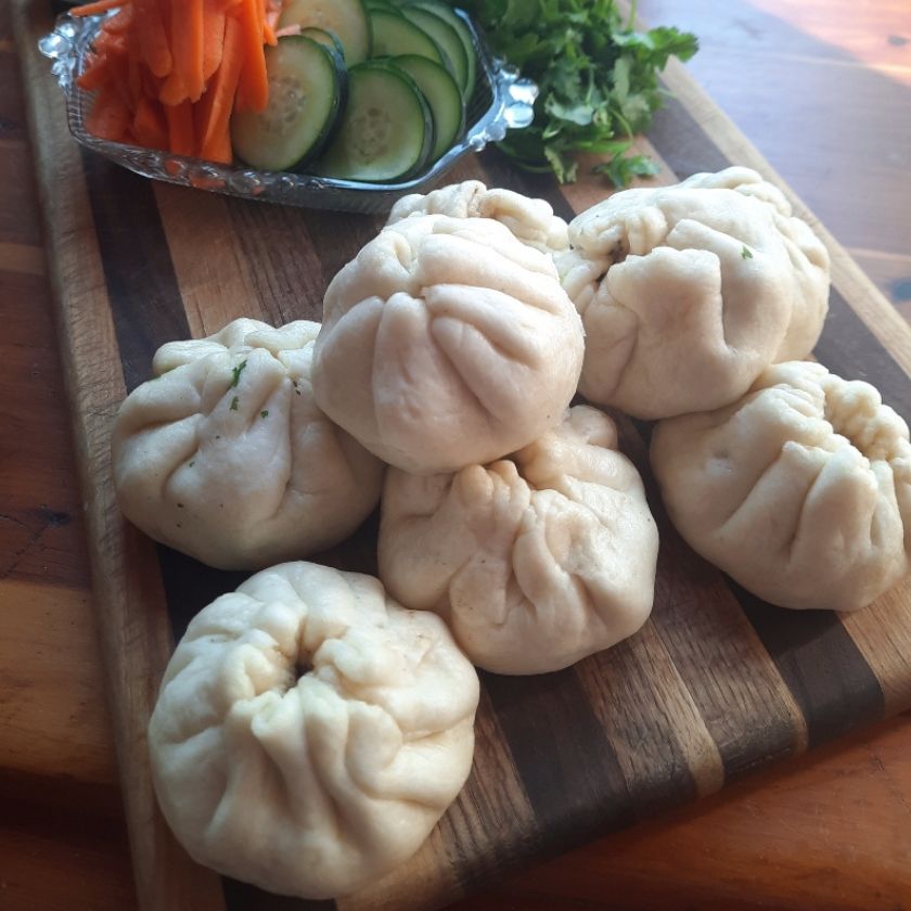 goat steam buns on a plate with cucumbers