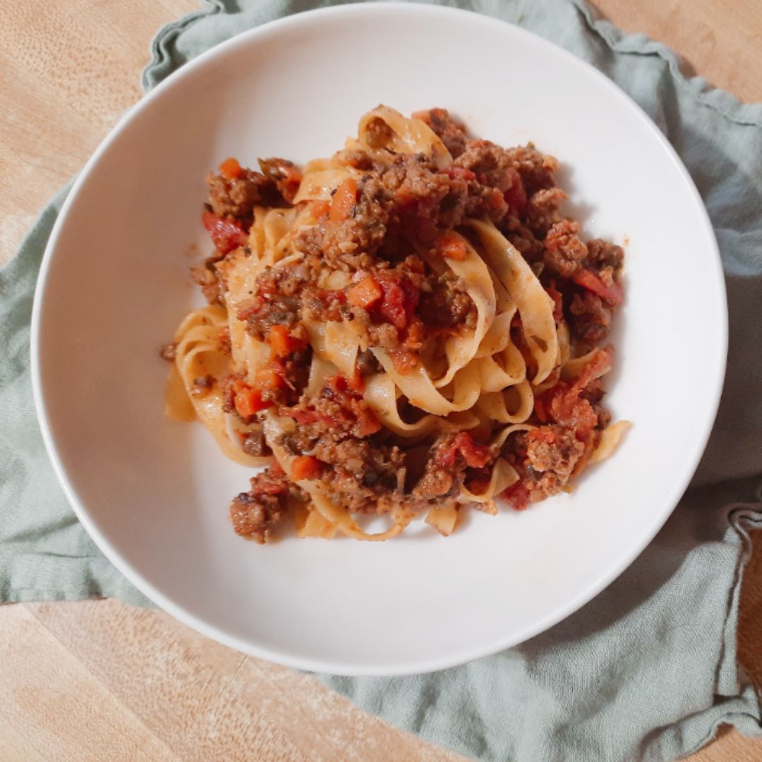 white bowl of goat bloganse on a wooden table with blue kitchen towel