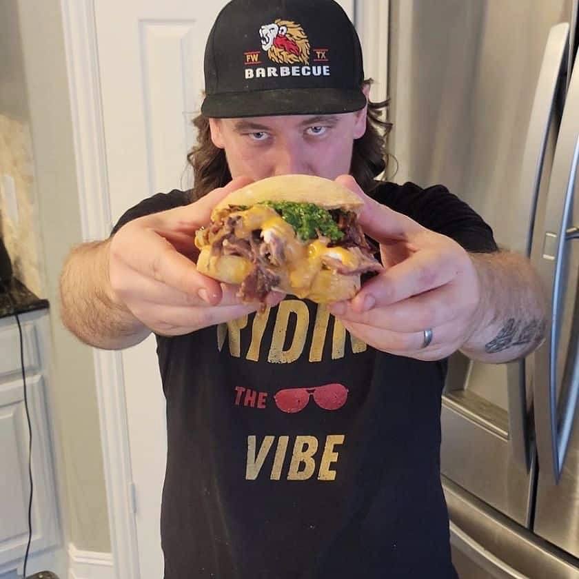 Grilling and Live Fire Food Creator Matt Rose holding a pulled goat sandwich