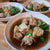 three bowls of wonton soup with cilantro on a wooden table